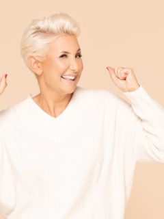 Portrait of confident adult woman with short blond hair looking at camera isolated over beige background in studio.