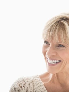 Close-up of happy mature woman looking away over white background